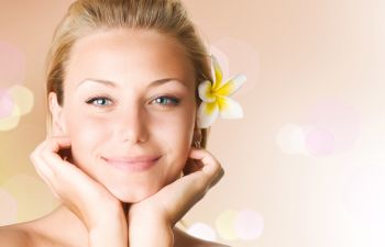 Youthful face of a beautiful woman wearing a flower in her hair.