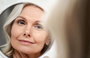 Mature woman examining her face in a mirror.